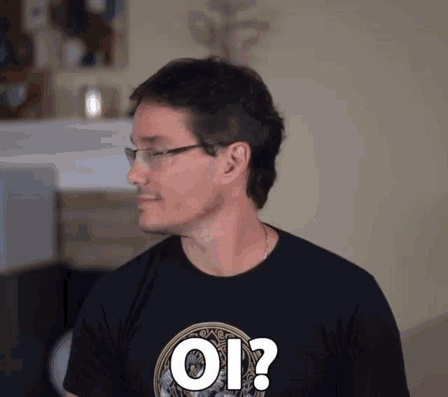 a man wearing glasses and a black shirt that says oi ?