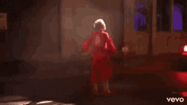 a woman in a red dress is dancing on a stage with a microphone .
