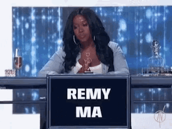 a woman sitting at a table with a sign that says remy ma .