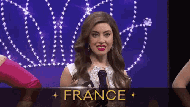 a woman is holding a microphone in front of a sign that says france .