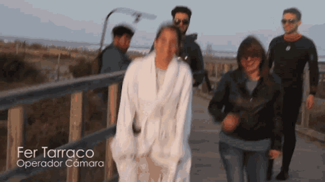 a group of people walking across a bridge with fer tarraco operator camara