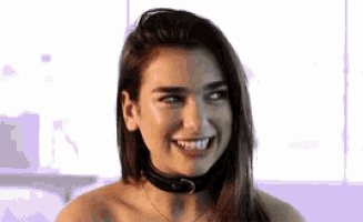 a woman with a choker around her neck is smiling and looking at the camera .