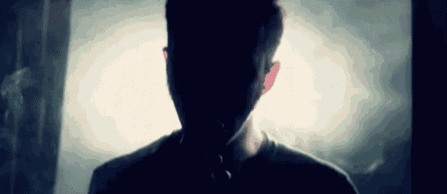 a man 's face is visible in a dark room with smoke coming out of the window .