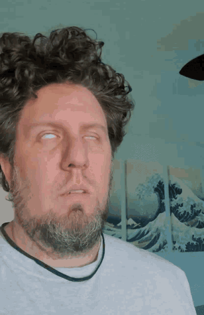 a man with a beard has his eyes closed in front of a picture of a wave