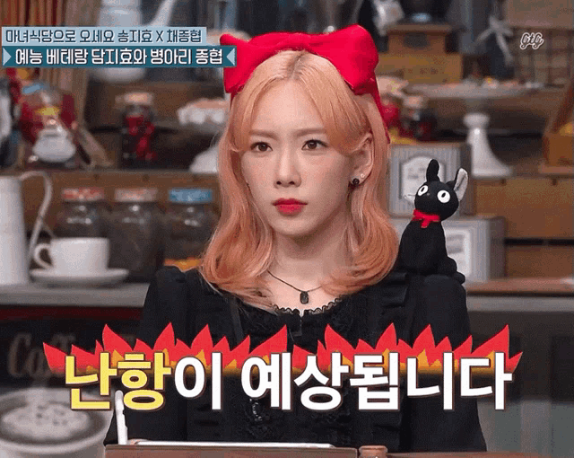 a woman with a red bow on her head is holding a stuffed black cat