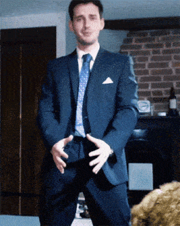 a man in a suit and tie holds his hands on his hips