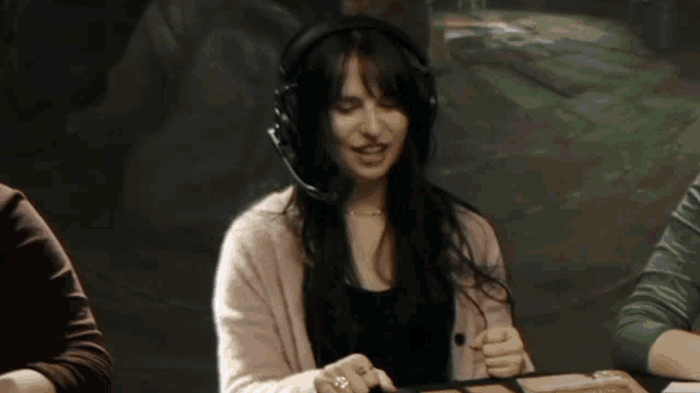 a woman wearing headphones sits at a table with a microphone