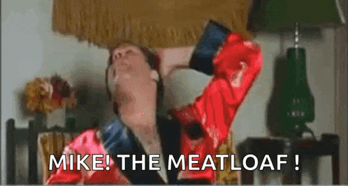 a man in a red robe is eating a loaf of meat loaf .