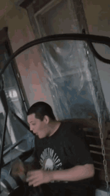 a man wearing a black shirt with a skull on it is sitting on a chair