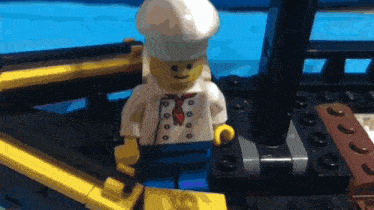 a lego chef wearing a white hat and a red tie