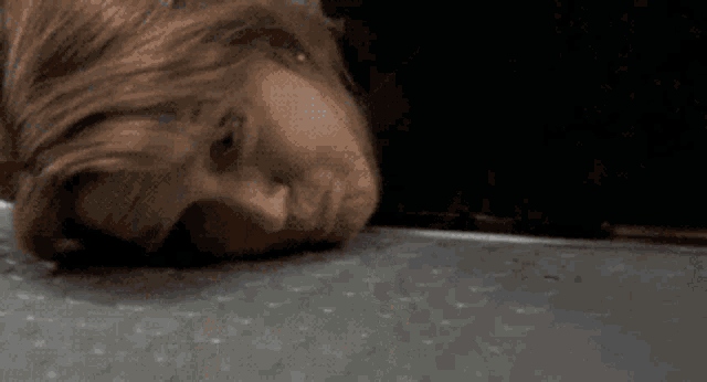 a close up of a person laying on a table with their head on the floor .
