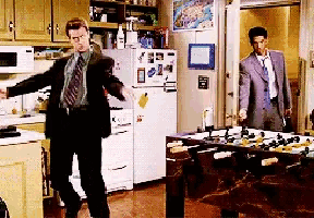 a man in a suit is dancing in a kitchen