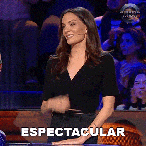 a woman is standing in front of a crowd and the word espectacular is on the screen behind her