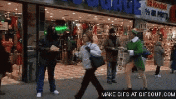 a group of people are walking in front of a store called kodak