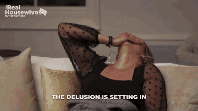 a woman sits on a couch with her head in her hands and the words the delusion is setting in