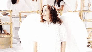 a woman in a white dress with angel wings laughing