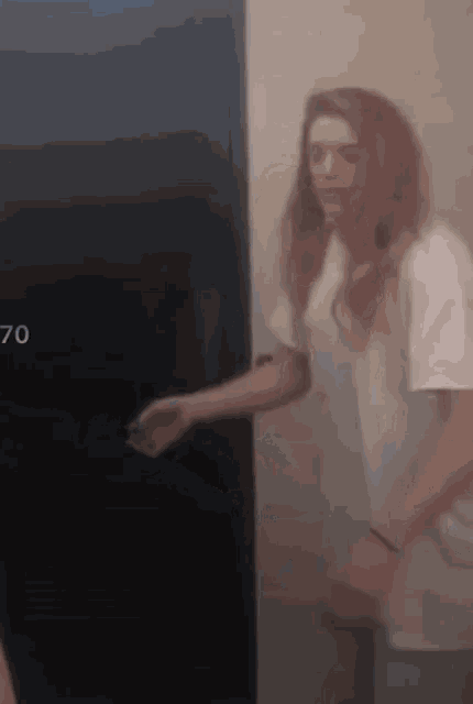 a woman is standing in front of a door that has the number 70 on it