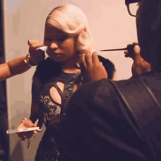 a woman with blonde hair is getting her makeup applied