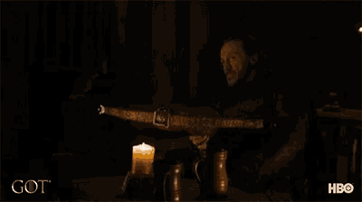 a man with a beard is holding a knife in front of a fireplace and the word got is on the bottom