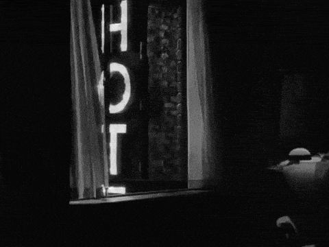 a black and white photo of a window with a sign that says hotel
