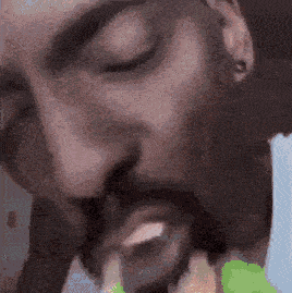 a close up of a man 's face with his eyes closed and a beard .