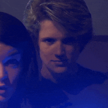 a man and a woman are posing for a picture in a dark room