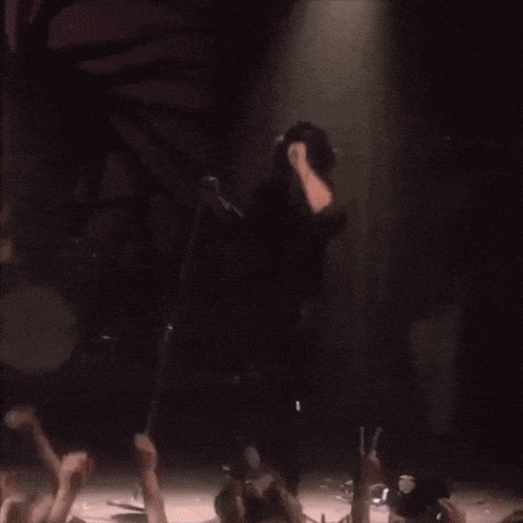a man is singing into a microphone with his arms in the air
