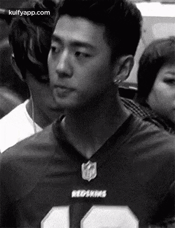a man in a redskins jersey is standing in a crowd .