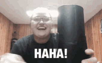 a man with glasses is holding a black object that says " haha "