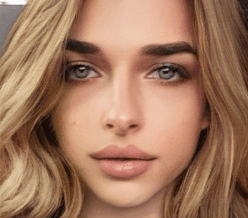 a close up of a woman 's face with blonde hair and gray eyes