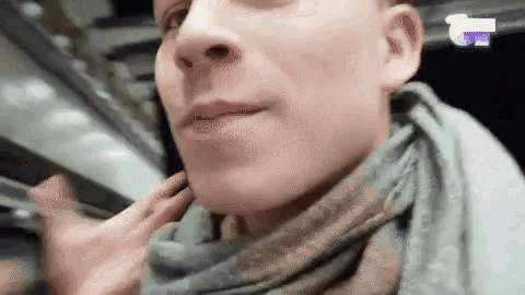 a man is wearing a scarf around his neck and talking on a cell phone .