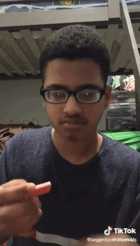 a young man wearing glasses is holding a slice of watermelon .