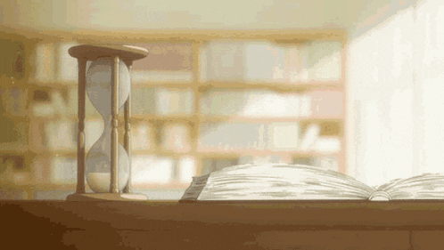 a hourglass is sitting on top of an open book on a table .