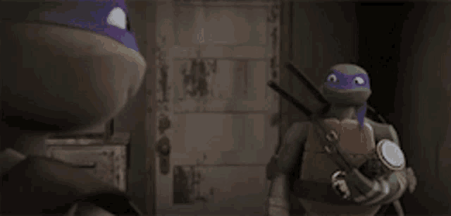 a couple of teenage mutant ninja turtles are standing next to each other in a dark room .