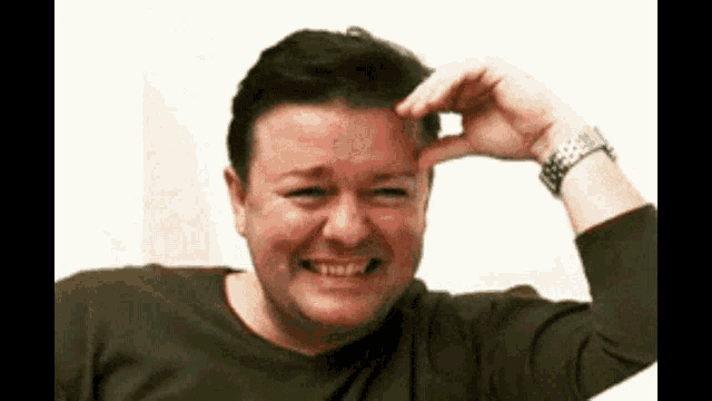 a man wearing a watch holds his hand to his forehead while making a funny face