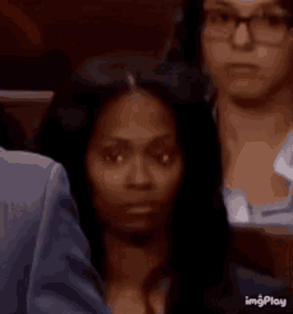 a woman wearing glasses is sitting in a row of people .