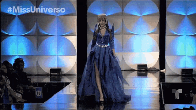 a woman in a blue dress walks down a runway with #missuniverso written on the bottom