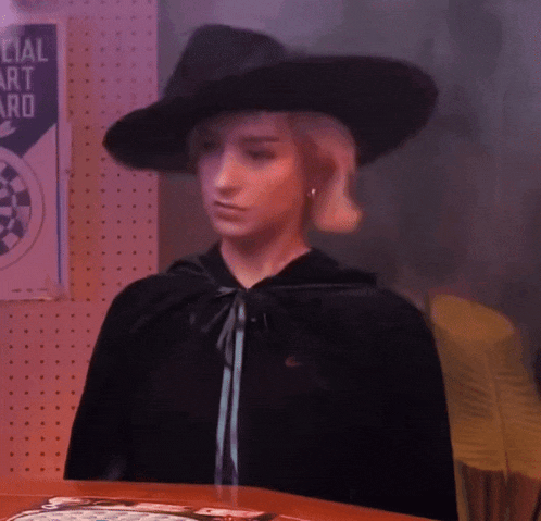 a woman wearing a black hat and cape stands in front of a special art award sign