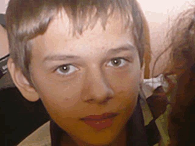 a close up of a young boy 's face with a blurred background and a sign that says ' sd '