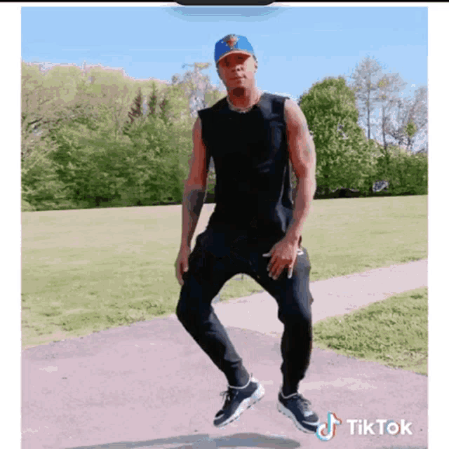 a man wearing a new york yankees hat is dancing in the park