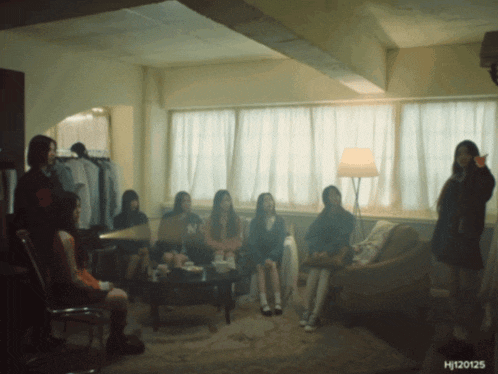 a group of women sitting in a living room with the number 12 on the wall