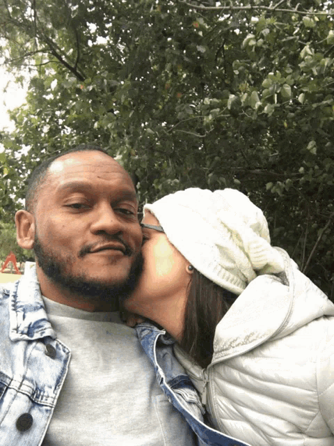 a woman in a white hat kisses a man in a denim jacket