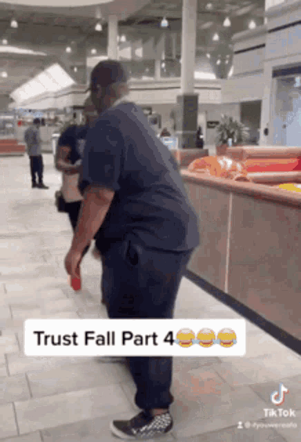 a man in a black shirt is standing in a shopping mall .