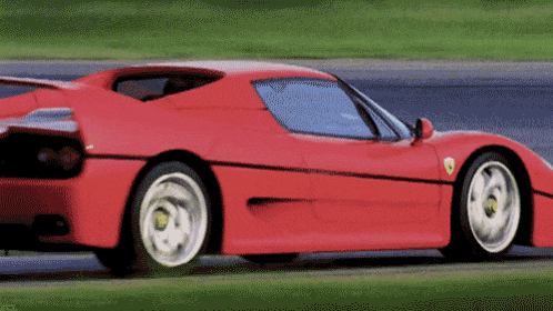 a red ferrari is driving on a road
