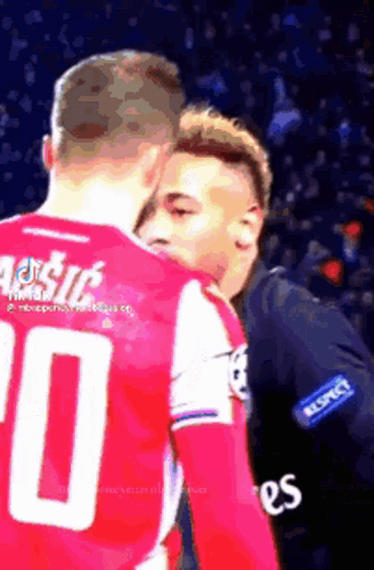 two soccer players are standing next to each other on the field .