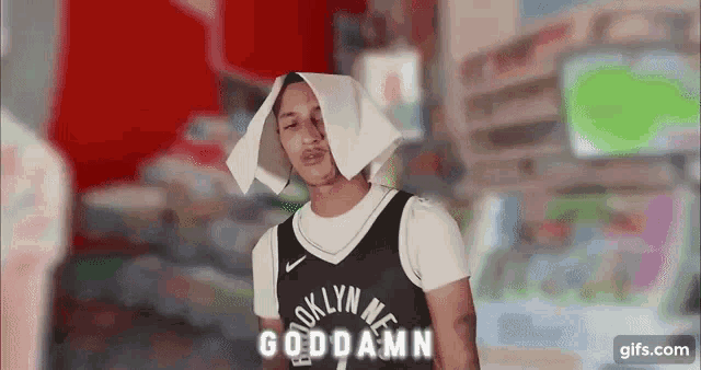a man wearing a brooklyn nets jersey is holding a piece of toilet paper on his head .