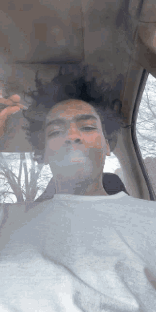 a man is smoking a cigarette while sitting in the back seat of a car .