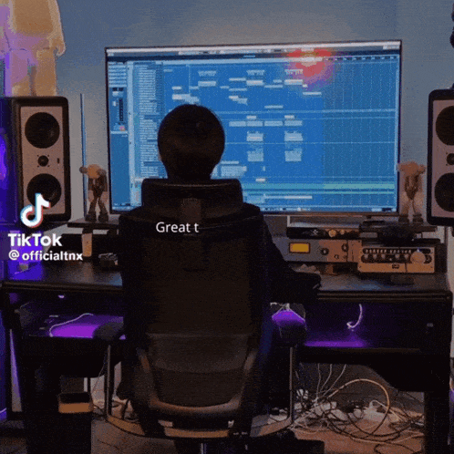 a person sitting in front of a computer with a great t written on the back of their chair