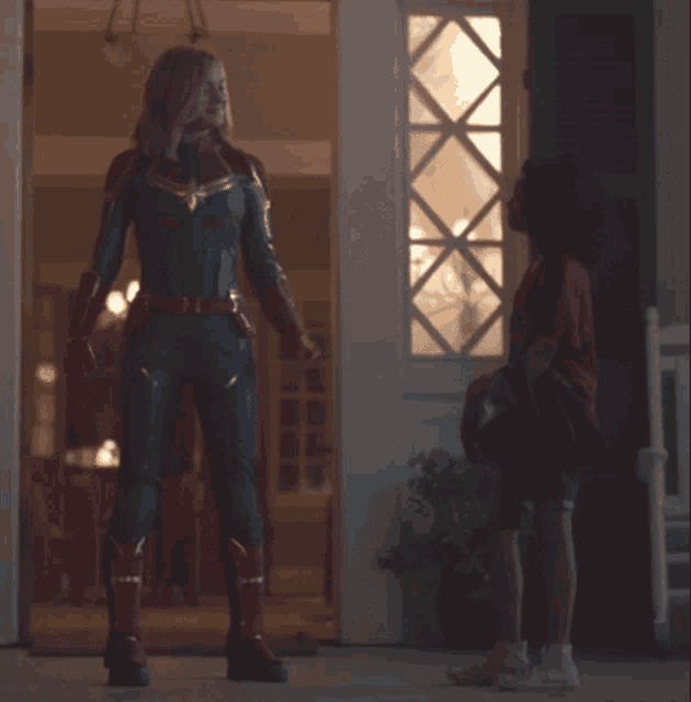 a woman in a superhero costume stands next to a child
