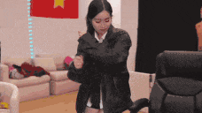 a woman in a black jacket is standing in front of a red flag